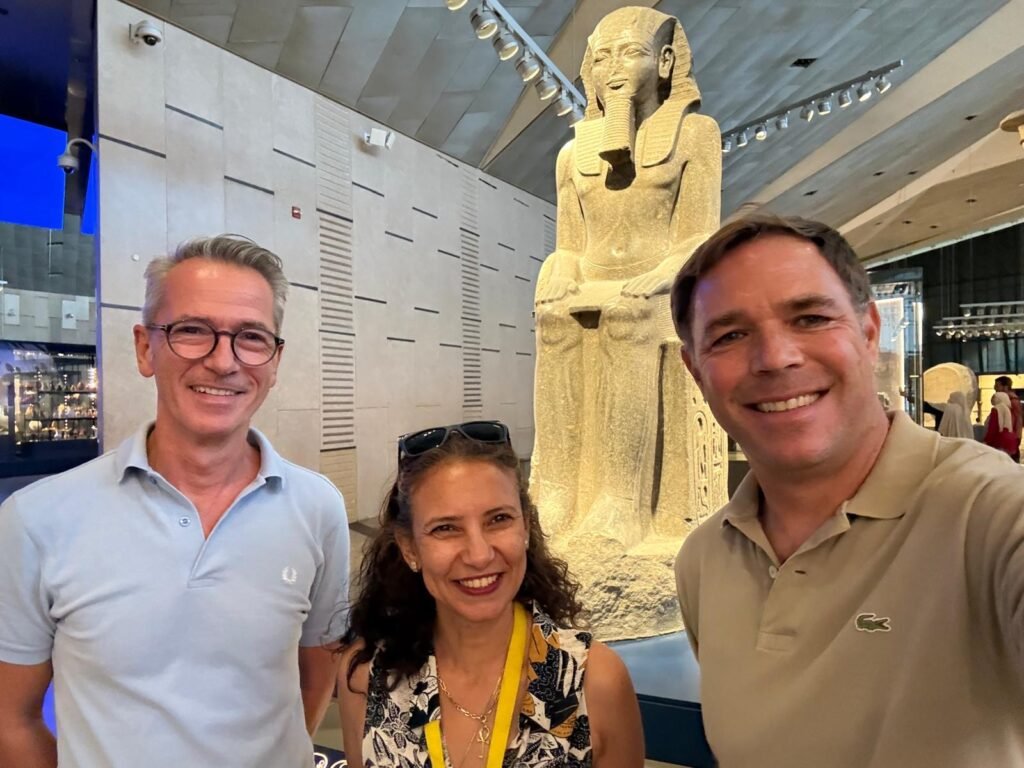 Azhaar Ahmed mit zwei Gästen vor einer sitzenden Statue Ramses’ II. in einer Galerie des Grand Egyptian Museum.